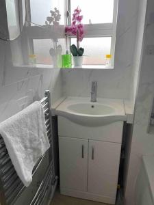 a white bathroom with a sink and a window at Fresh Apartment & Parking in London