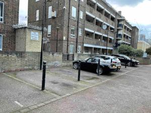 dos autos estacionados en un estacionamiento frente a un edificio en Fresh Apartment & Parking, en Londres