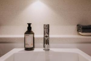 a bottle of soap sitting on a bathroom sink at Twilight Olympic Park 2x King-beds Lux Apt in Sydney