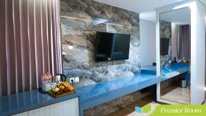 a bathroom with a tv on a stone wall at Hotel Ayola Sunrise Mojokerto in Mojokerto