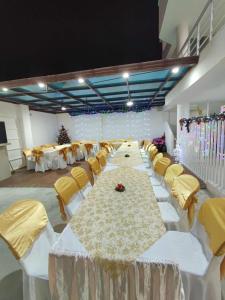 Hostería Luz Del Mar في تونسوبا: قاعة احتفالات كبيرة مع طاولات بيضاء وكراسي صفراء