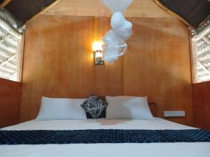 a bed with white pillows and a light fixture at Pidurangala View Treehouse in Sigiriya