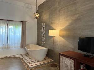 a bathroom with a bath tub and a lamp and a television at Dontrei Villa Angkor in Siem Reap