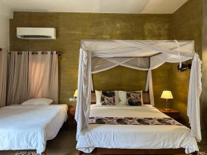 a bedroom with two beds and a canopy bed at Dontrei Villa Angkor in Siem Reap