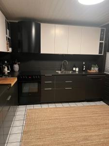 uma cozinha com armários a preto e branco e um lavatório em Lykkja - Beautiful Waterfront House em Viggja