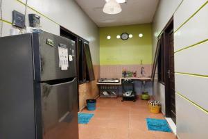 a kitchen with a refrigerator and a clock on the wall at Griya Sakura Syariah in Solo