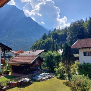 a wooden house with a mountain in the background at Haus Kurparkblick Ferienwohnung Lautersee in Mittenwald