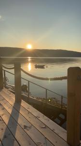 słońce zachodzące nad zbiornikiem wody z molo w obiekcie Lykkja - Beautiful Waterfront House w mieście Viggja
