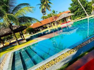 una piscina frente a una casa con palmeras en BLUE WAVES kite surfing beach resort, en Kalpitiya