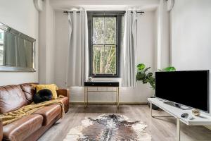 ein Wohnzimmer mit einem Sofa und einem TV in der Unterkunft The Stylist's House - A Chic Inner City Landmark in Sydney