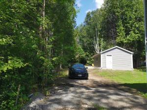 a car parked on a dirt road next to a garage at Pigeon Lake Cottage in Kawartha Lakes