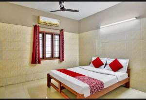 a bedroom with a bed with red pillows and a window at RK RESIDENCY INN in Chennai