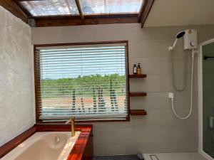 a bathroom with a tub and a window and a shower at กระบองแพะ in Ban Nong Khwang