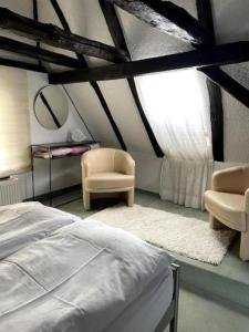 ein Schlafzimmer mit einem Bett, einem Stuhl und einem Fenster in der Unterkunft Ferienwohnung im 'Schmoller - Hof' in Neustadt an der Weinstraße