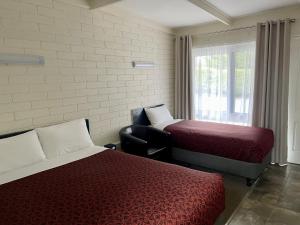 een kamer met 2 bedden, een stoel en een raam bij Central Highlands Motor Inn in Kyneton