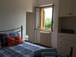 a bedroom with a bed with a blue blanket and a window at Casa Roda in Castiglione del Lago
