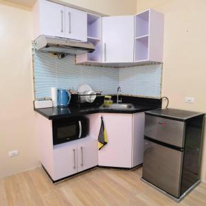 Elle comprend une petite cuisine avec des placards blancs et un réfrigérateur noir. dans l'établissement Avida Davao by davaobnb & Lemonique Homes, à Davao