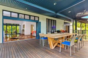 una gran terraza con mesa y sillas de madera en Golden Sands Retreat Beach House en Wagait Beach
