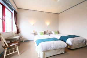 um quarto com duas camas e uma cadeira e uma janela em Naughty Cao em Yamanakako