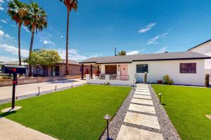 a house with a green yard with palm trees at Pink Door Place in Phoenix