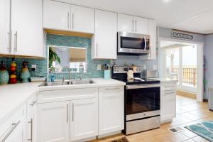 a kitchen with white cabinets and a sink and a microwave at Oyster Drive Bungalow in Port Isabel