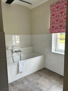 a white bathroom with a tub and a window at Storchenhof Blumenow in Blumenow