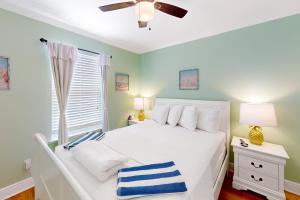 a bedroom with a white bed and a ceiling fan at Sunsets & Sunrises in Panama City Beach