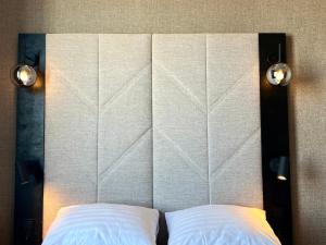 ロヴァニエミにあるサンタズ ホテル サンタ クロースの白い枕2つと照明2つ付きのヘッドボード