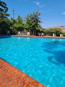 a large blue swimming pool with two white chairs at Sail Away Camogli in Camogli