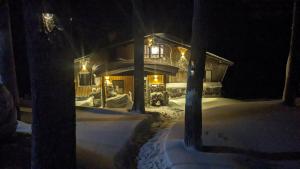 a house in the snow at night with lights at Japan Snowsports in Iiyama