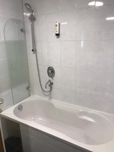 a white bath tub with a shower and a sink at Hotel Mautner Airport und Messehotel in Stuttgart
