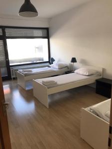 2 Betten in einem Zimmer mit einem großen Fenster in der Unterkunft Hotel Mautner Airport und Messehotel in Stuttgart