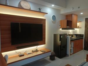 a kitchen with a flat screen tv and a refrigerator at Yukari Seturan Yogyakarta at Altuz Apartment in Yogyakarta