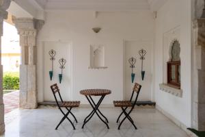 a table and two chairs in a room with a wall at Sardargarh Heritage Fort Udaipur in Sardārgarh