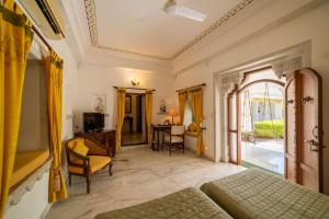 a bedroom with a bed and a desk and a window at Sardargarh Heritage Fort Udaipur in Sardārgarh