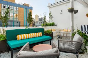a green bench on a balcony with chairs and a table at The Carrington Aparthotel by Totalstay in Cape Town