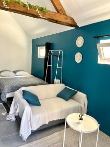 ein Zimmer mit 2 Betten und einem Sofa und einer blauen Wand in der Unterkunft Studio avec grand jardin + parking in Seraincourt