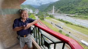a man standing on a balcony with a view of a bridge at 知本富爺飯店Chihpen Fuye Hotel in Wenquan