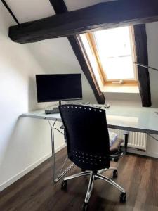 a desk with a computer and a chair in a room at Ferienwohnung im 'Schmoller - Hof' in Neustadt an der Weinstraße