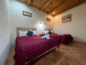 two beds in a room with red comforter and pillows at Casa del viajero colonial in Antigua Guatemala