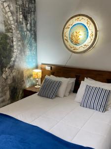 a bed with blue and white pillows and a clock on the wall at POUSADA CHARLOTTE in Tiradentes +290 photos