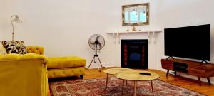 sala de estar con sofá amarillo y TV de pantalla plana en The Quince & Olive en Parys