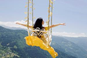 a woman sitting on a swing in the sky at Nika Hotel and Club in Chʼanchʼkhalo