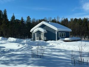 ein blaues Gebäude im Schnee mit Bäumen im Hintergrund in der Unterkunft SINITALO in Inari