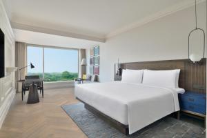 a bedroom with a large white bed and a desk at Le Meridien Amritsar in Amritsar