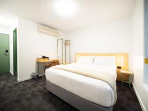 um quarto com uma grande cama branca e uma secretária em YHA Brisbane City em Brisbane