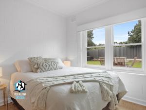 een witte slaapkamer met een bed en een raam bij Just Renovated in the Heart of Pt Elliot in Port Elliot