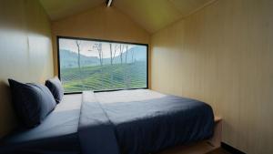 - une chambre avec un lit et une grande fenêtre dans l'établissement Bobocabin Pangalengan, Bandung, à Pengalongan