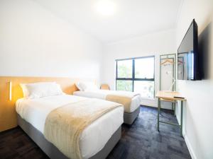 a hotel room with two beds and a tv at Brisbane City YHA in Brisbane
