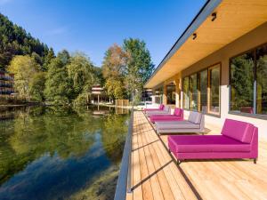 eine Reihe von lila Stühlen auf einer Terrasse neben dem Wasser in der Unterkunft Vivea Gesundheitshotel Eisenkappel in Bad Eisenkappel